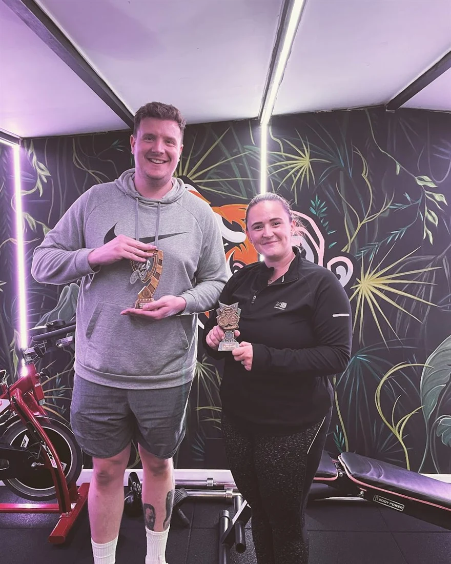 Two JungleFit members holding award trophies in the studio