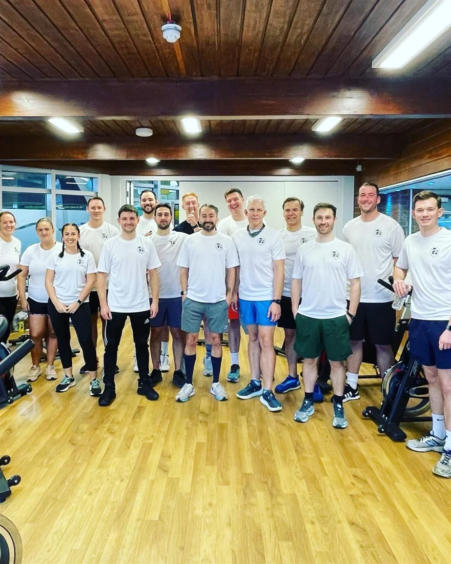 A large JungleFit group in matching white T-shirts at an indoor event