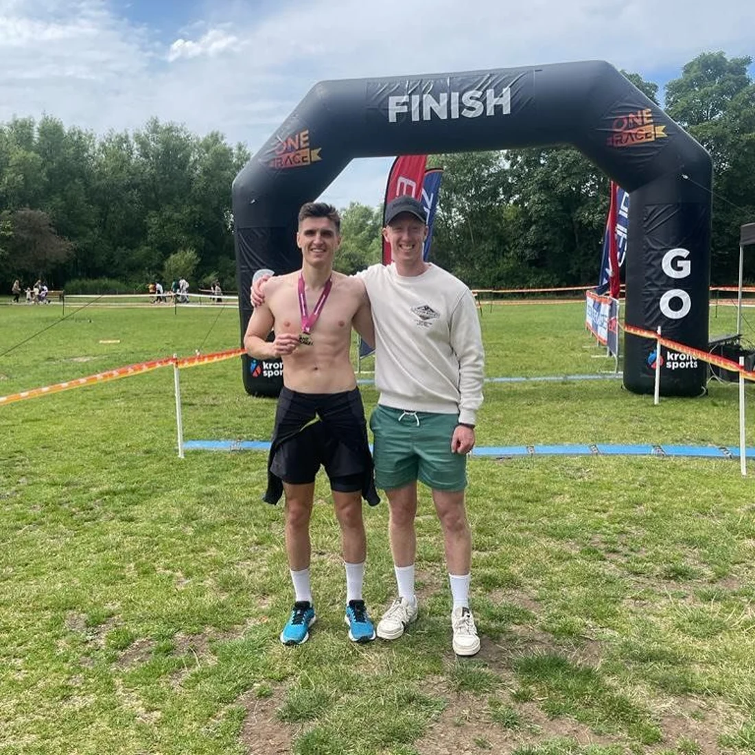 Two JungleFit members at a race finish arch, one wearing a medal