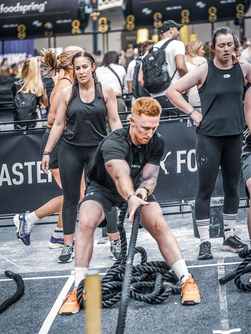 JungleFit members competing at a fitness event, one working the battle ropes